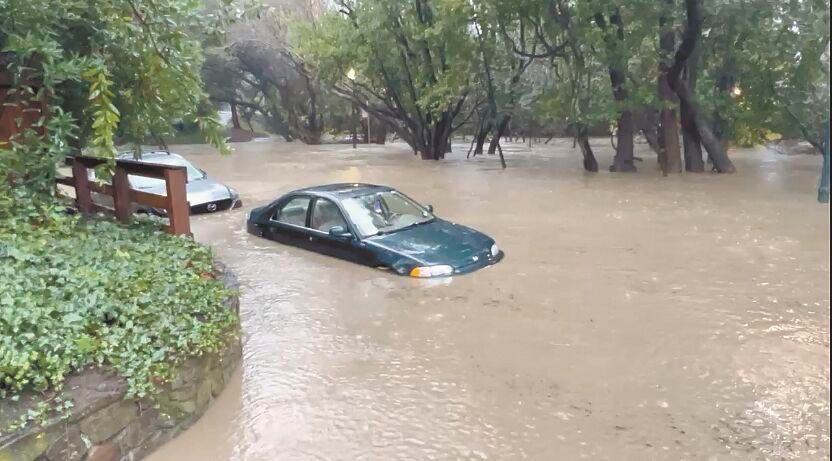 A flooded street with two cars submerged in the water